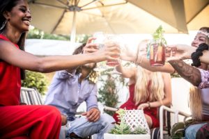 During a spring birthday party friends sitting in a cirle cheering their drink glasses with one another